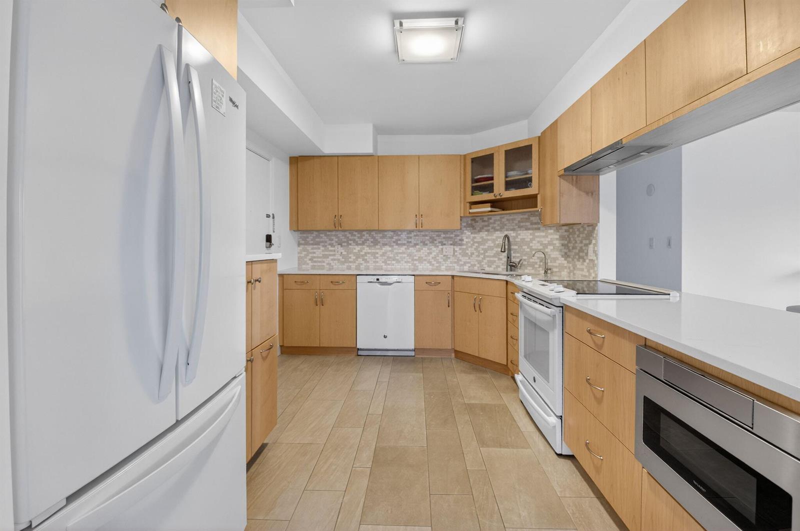 A kitchen with light wood cabinets, white appliances, white countertops, and a tiled backsplash — 1000 Lowry Street # 3e, Delray Beach FL 33483, DELRAY BEACH, FL