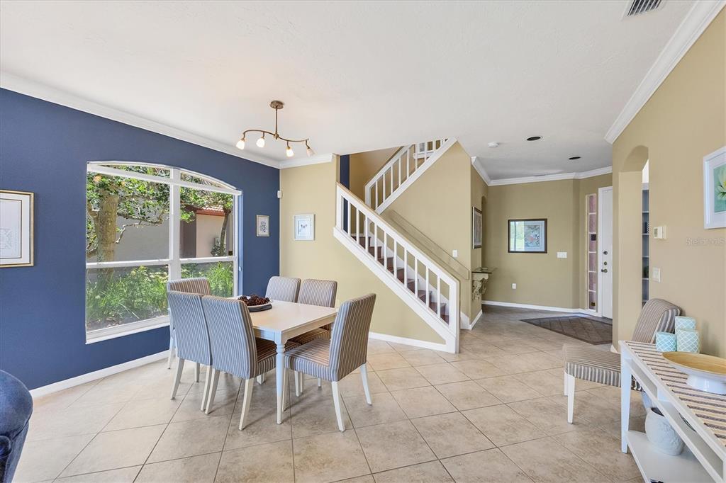A dining area with a blue accent wall, tiled floors, and a staircase — 7263 REGINA ROYALE UNIT 3, SARASOTA, FL