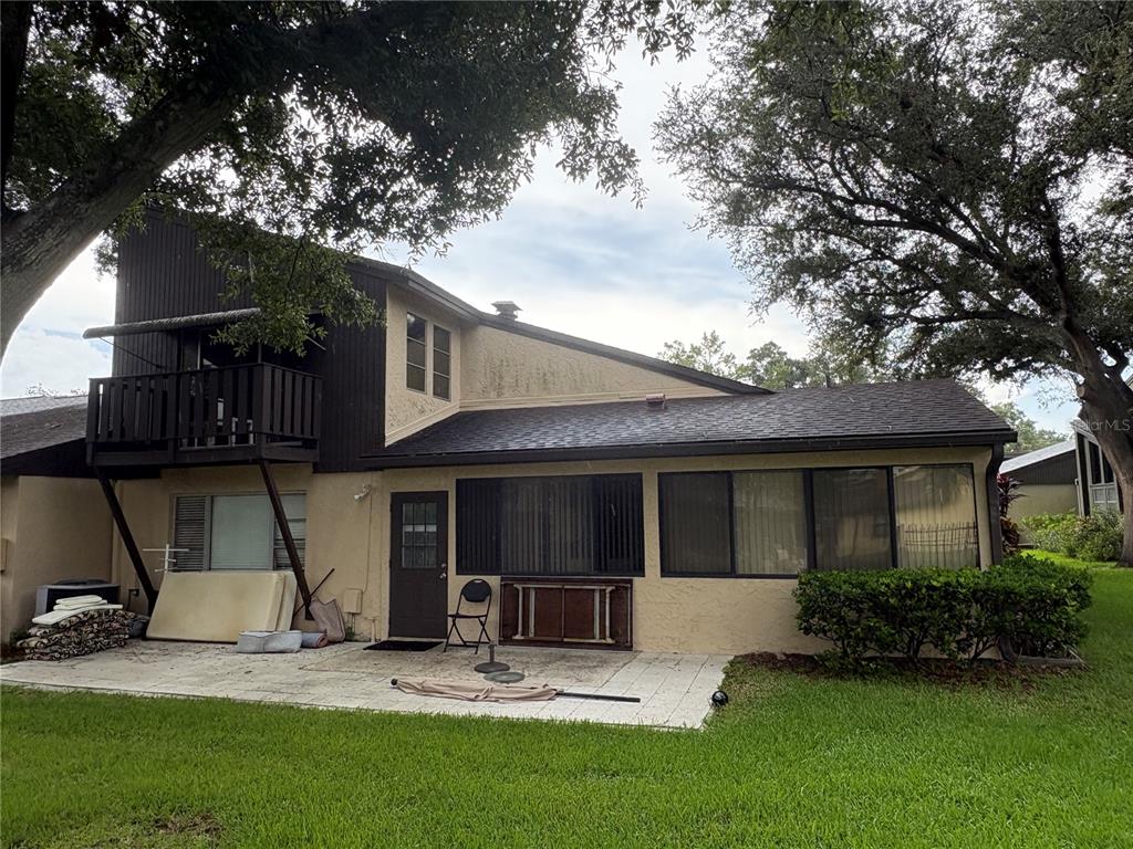The exterior of a two-story house features a balcony, a patio, and a grass lawn — 2101 SUNSET POINT ROAD UNIT 2105, CLEARWATER, FL