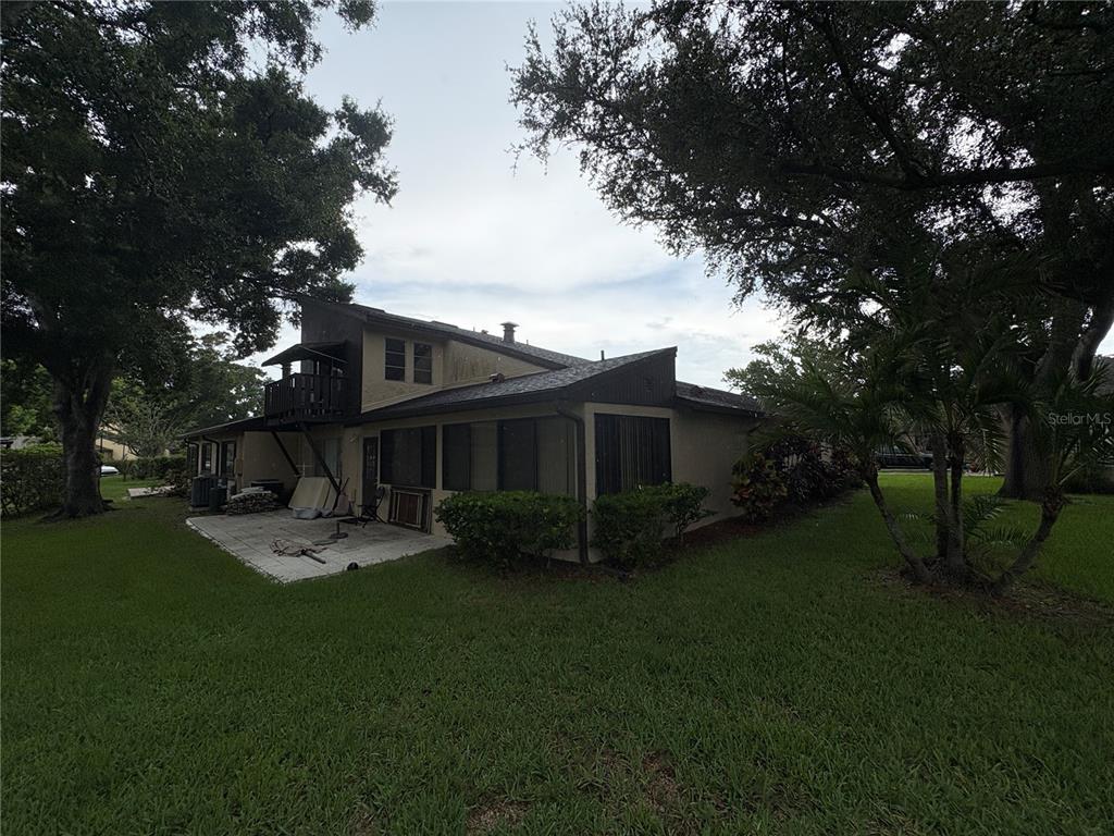 The exterior of a two-story house features a patio, a balcony, and surrounding trees — 2101 SUNSET POINT ROAD UNIT 2105, CLEARWATER, FL