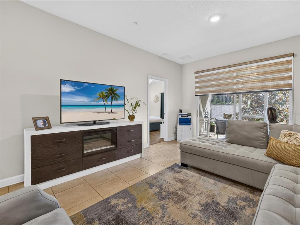 A living room features a TV console with a fireplace, a sectional sofa, and tile flooring — 3530 FAIRWATERS COURT UNIT D, CLERMONT, FL