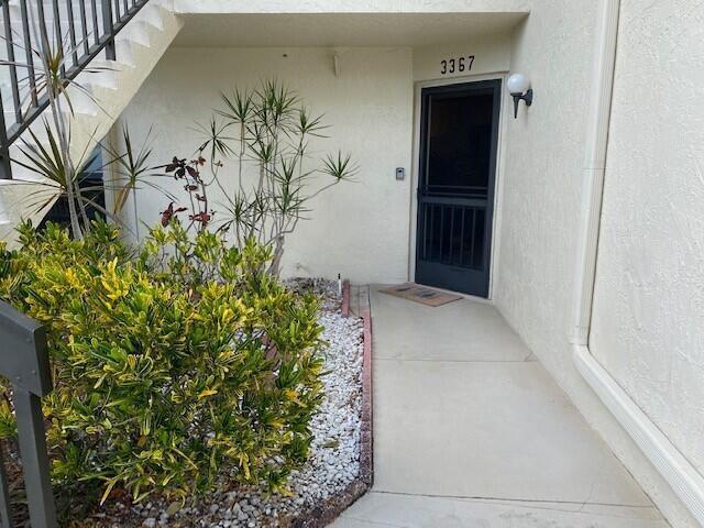 A concrete walkway leads to the front entrance of a building with a screen door — 3367 Perimeter Drive, FL 33467, FL