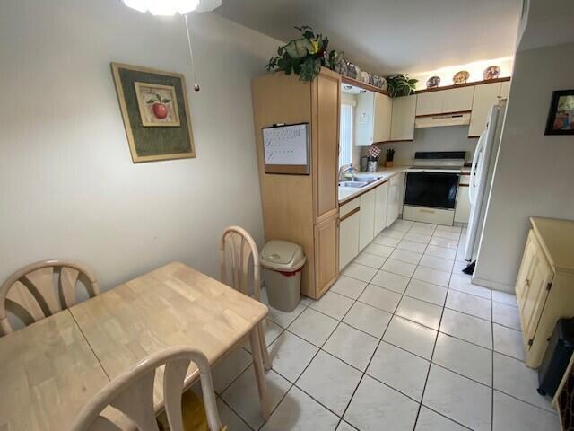 A kitchen with light wood cabinets, white tile flooring, and an adjacent dining area — 3367 Perimeter Drive, FL 33467, FL