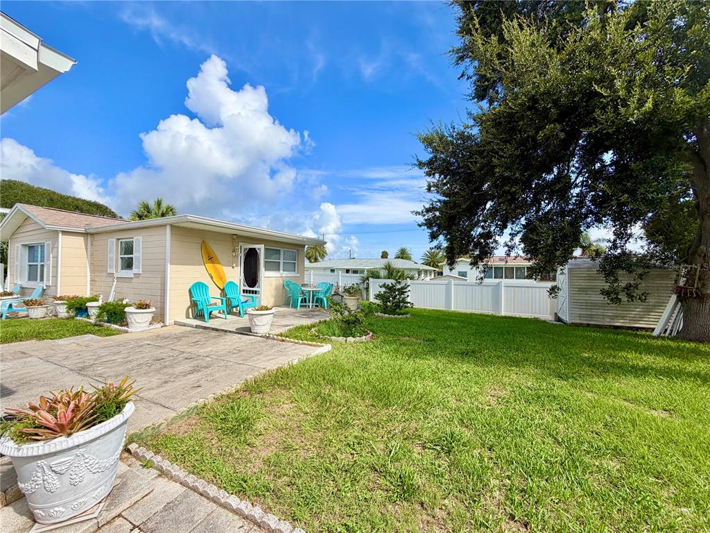 A tan house with a concrete patio, bright blue chairs, and a large tree in the yard — 233 WILLIAMS AVENUE, DAYTONA BEACH, FL