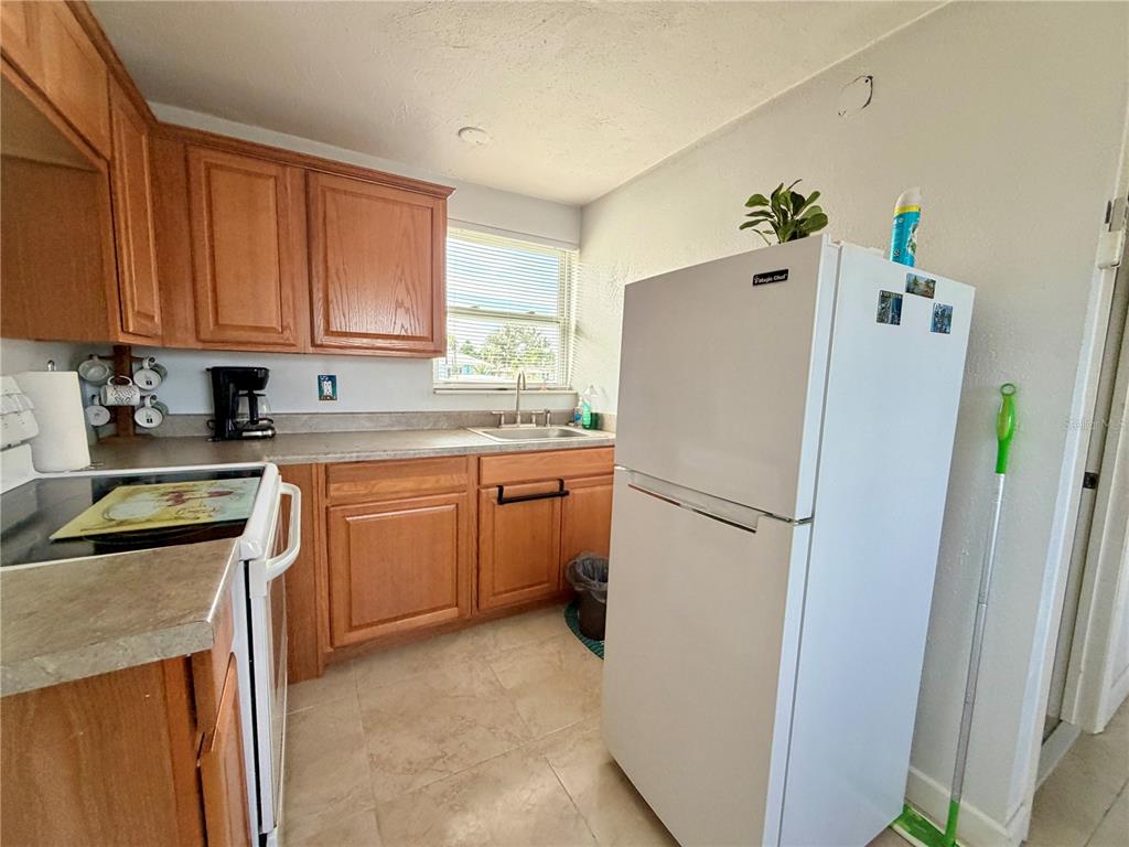 A kitchen features light wood cabinets, a white refrigerator, and a window above the sink — 233 WILLIAMS AVENUE, DAYTONA BEACH, FL