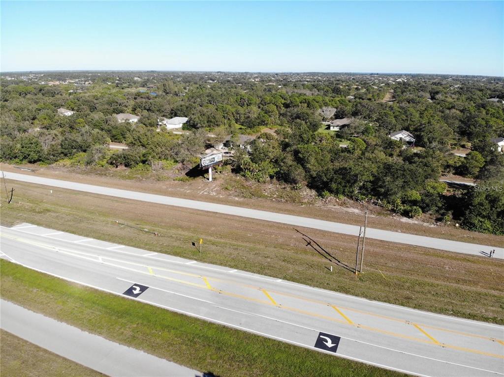 An aerial view shows a highway running alongside a wooded area with a billboard — 10080 WINBOROUGH DRIVE, PORT CHARLOTTE, FL
