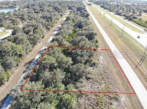 An aerial view shows a rectangular plot of land outlined in red next to a highway — 10080 WINBOROUGH DRIVE, PORT CHARLOTTE, FL