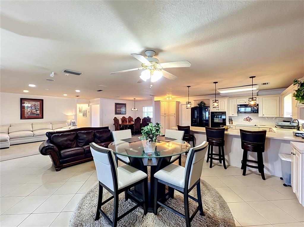 An open-concept kitchen, dining area, and living room featuring tile floors and a glass table — 2404 LAUDERDALE COURT, ORLANDO, FL