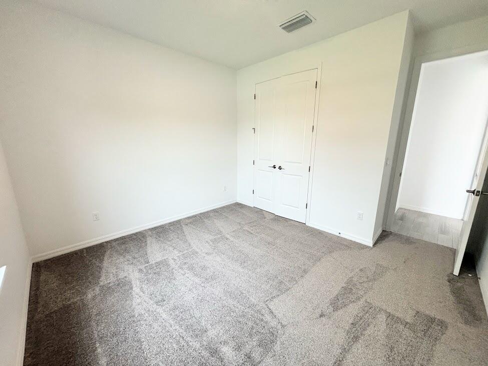 An empty bedroom features white walls, gray carpeting, and a set of double closet doors — 9299 SW Lorenzo Way, FL 34987, FL