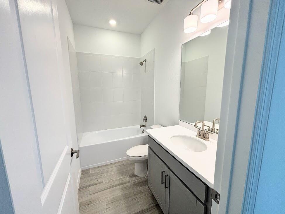 A bathroom features a gray vanity, white countertop, toilet, and a shower-tub combo — 9299 SW Lorenzo Way, FL 34987, FL
