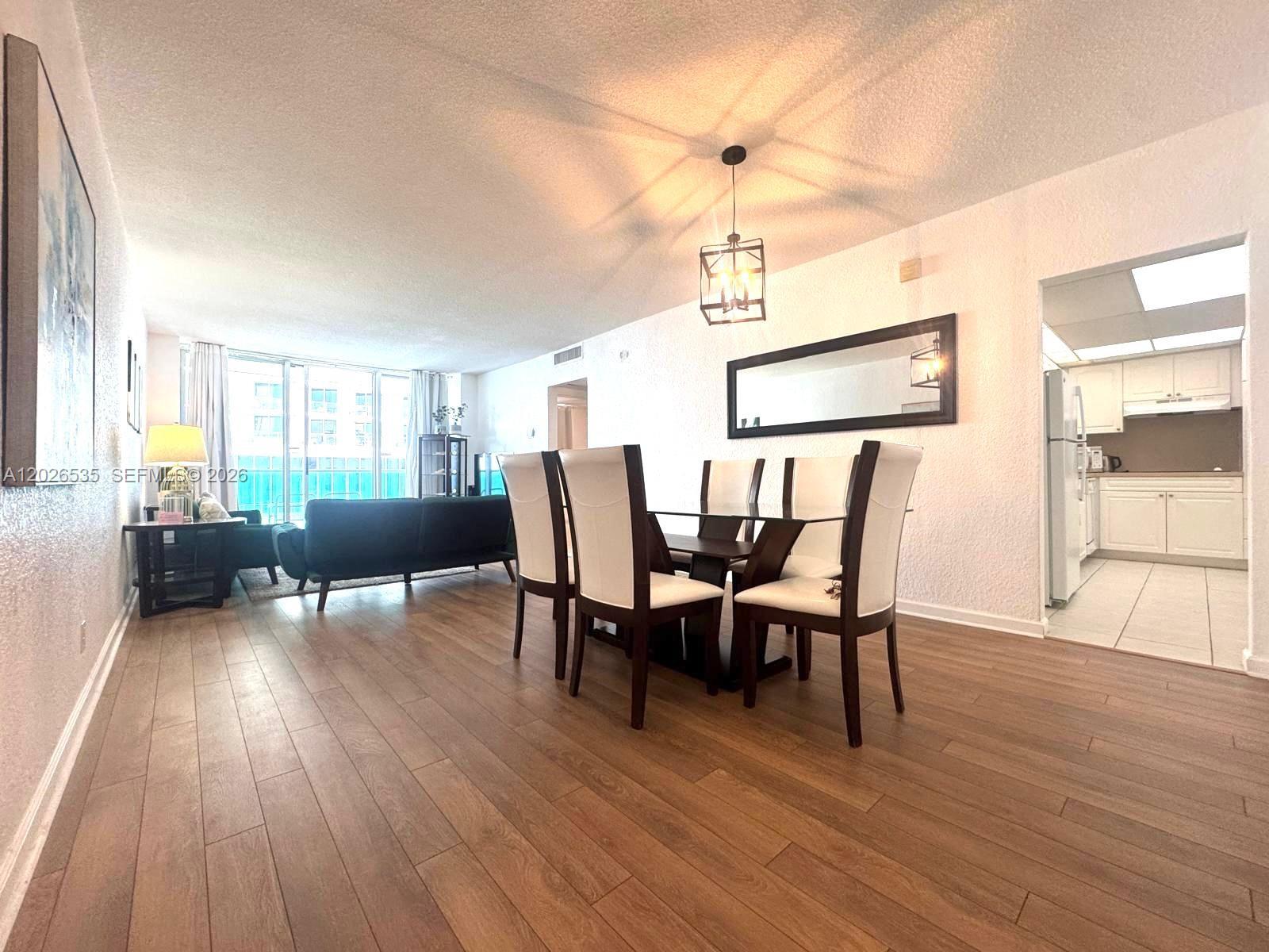A dining area with a glass table and chairs sits adjacent to a living room — 4001 S Ocean Dr # 15L, Hollywood FL 33019, HOLLYWOOD, FL