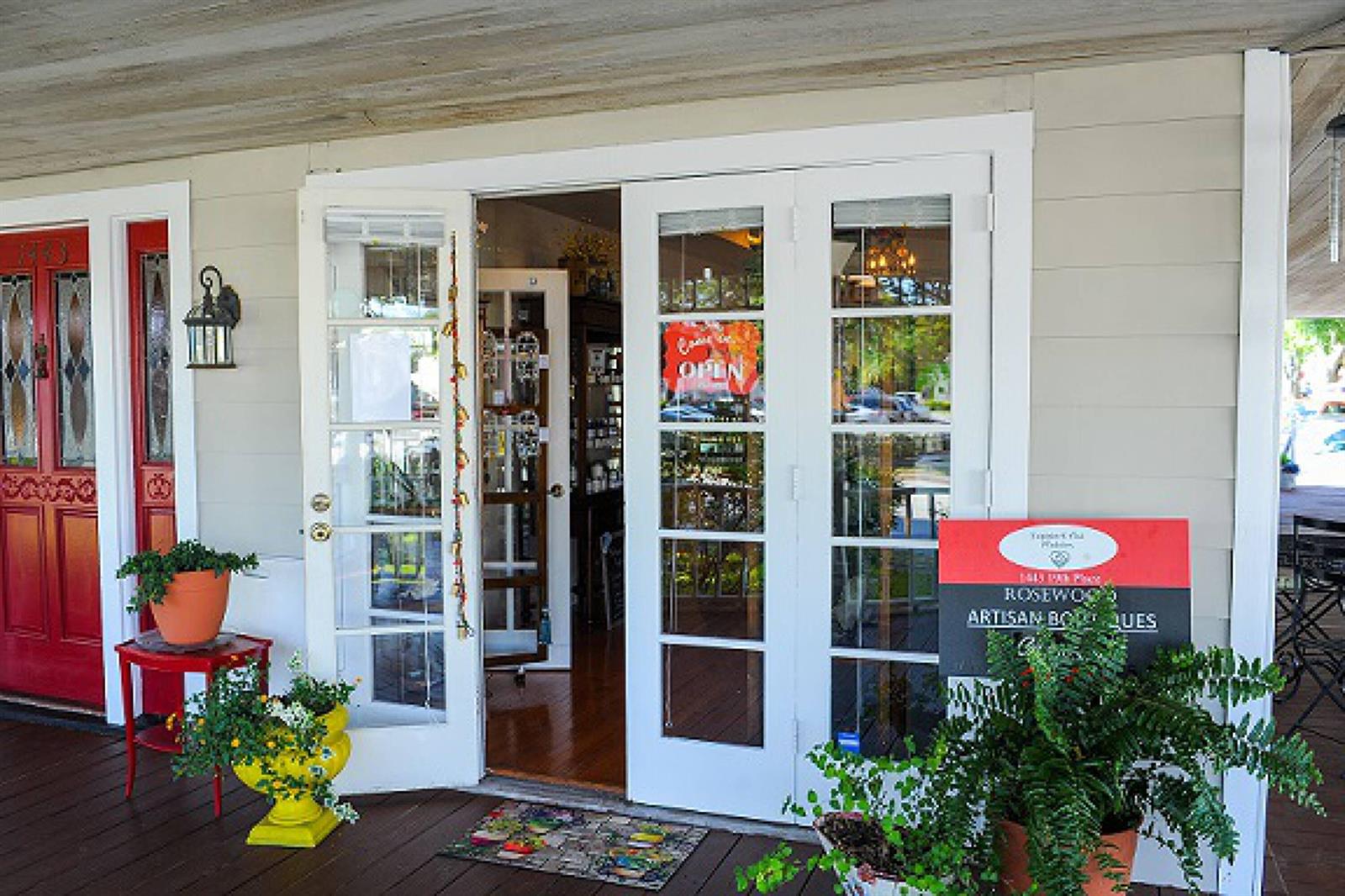The exterior entrance of a shop features white French doors, a red door, and potted plants — 1443 19th Place, Vero Beach FL 32960, VERO BEACH, FL