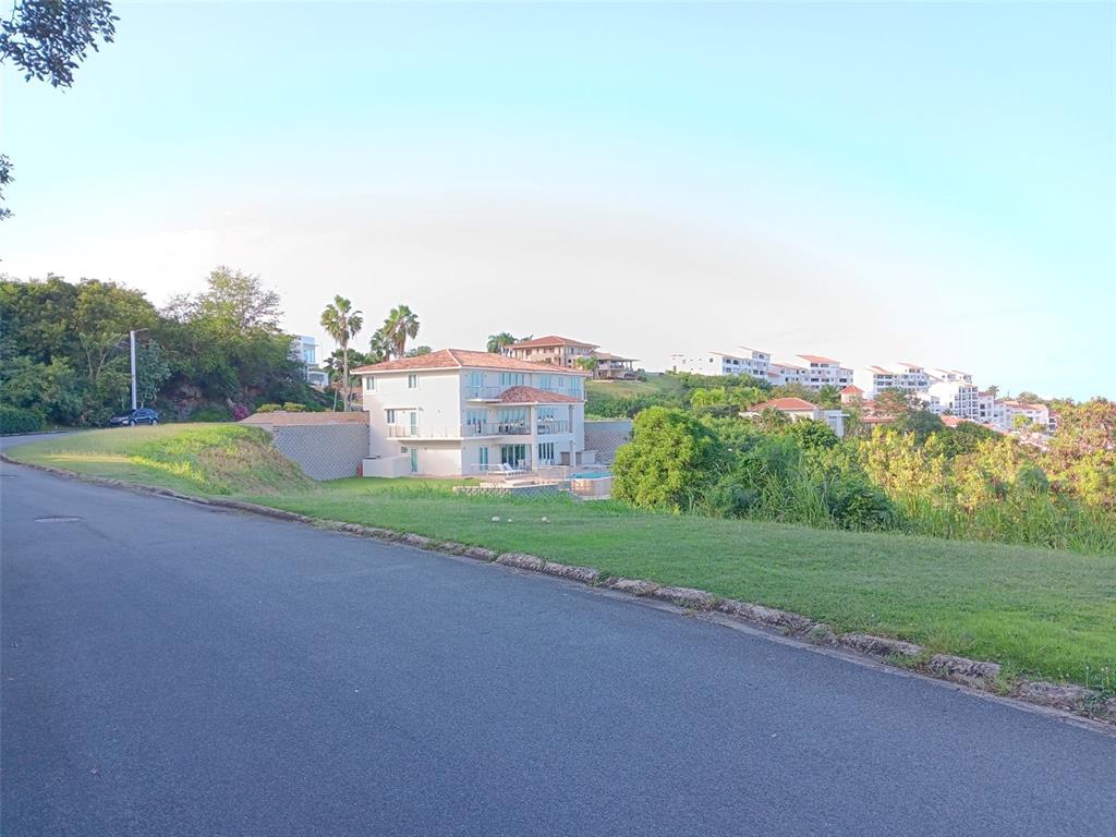 A multi-story house with a tiled roof sits on a grassy hill near a road — 6000 RIO MAR BOULEVARD Lot 53, RIO GRANDE, PR