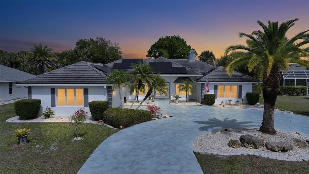 A single-story house with a gray tiled roof, solar panels, and a curved concrete driveway — 194 MARACAL WAY, PUNTA GORDA, FL