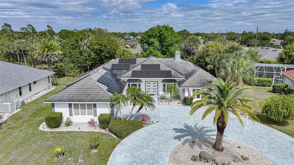 An aerial view shows a single-story house with a tiled roof, solar panels, and driveway — 194 MARACAL WAY, PUNTA GORDA, FL