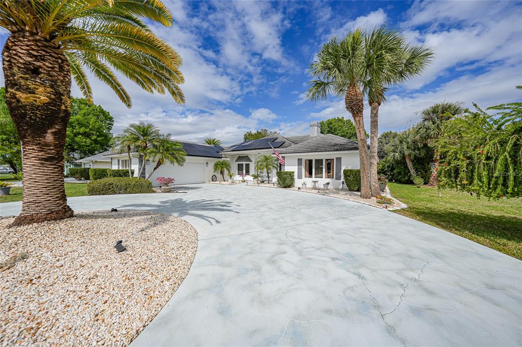 A white single-story house with a large concrete driveway and palm trees in the front — 194 MARACAL WAY, PUNTA GORDA, FL
