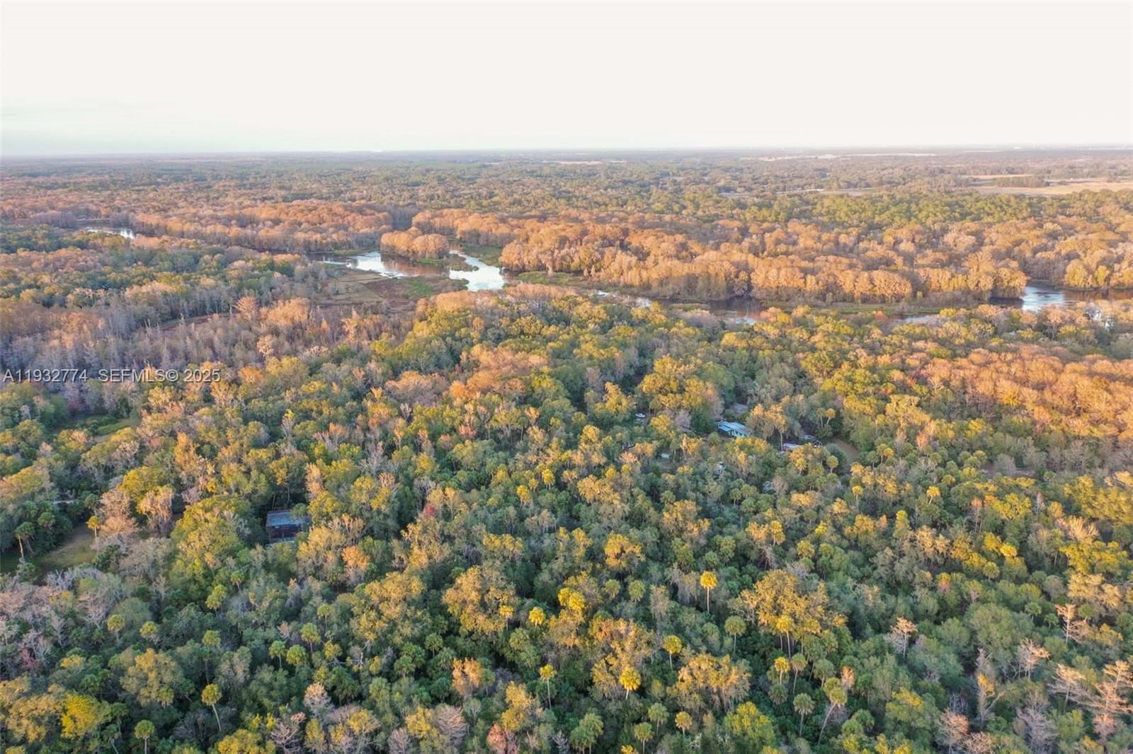 An aerial view shows a dense forest landscape with a winding river in the background — 13254 E SHAWNEE TRL, Inverness FL 34450, INVERNESS, FL