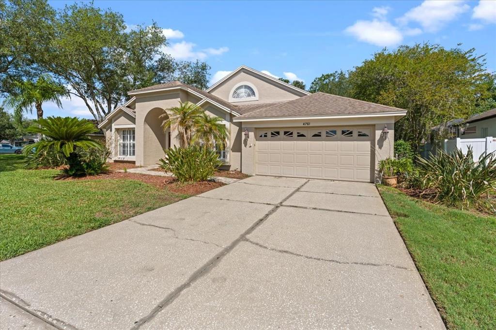 A single-story house with a beige stucco exterior, a two-car garage, and a concrete driveway — 4761 STONEBRIAR DRIVE, OLDSMAR, FL