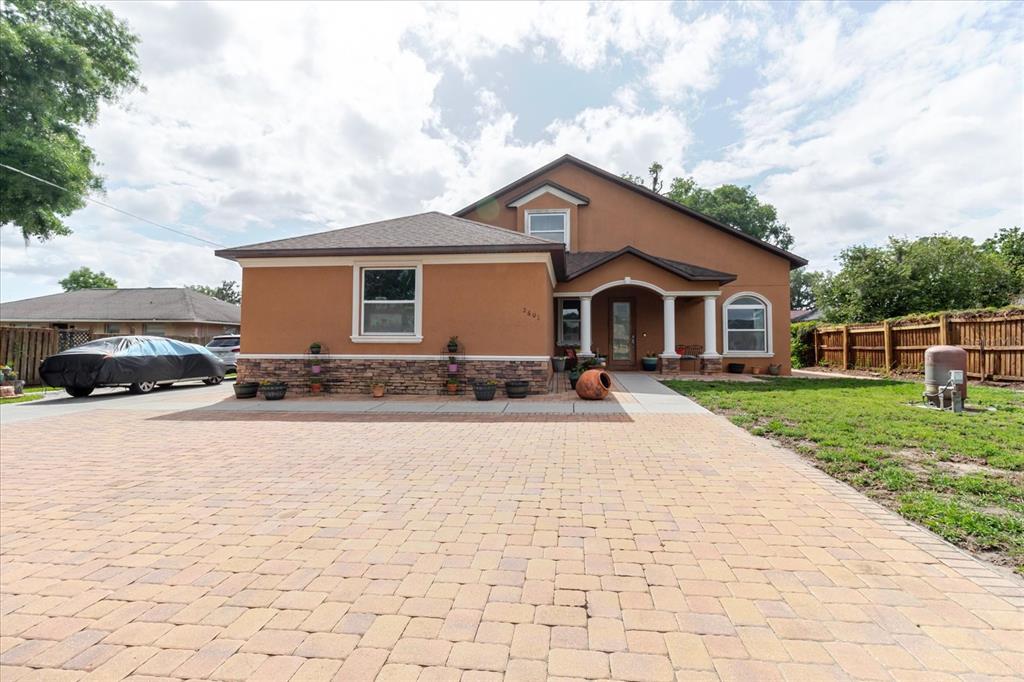 A two-story house with a tan stucco exterior, stone veneer base, and a paved driveway — 2603 BISMARK DRIVE, VALRICO, FL