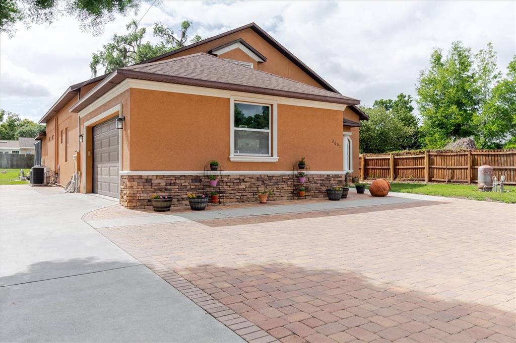 A side view of a house with an orange stucco exterior, stone base, and driveway — 2603 BISMARK DRIVE, VALRICO, FL
