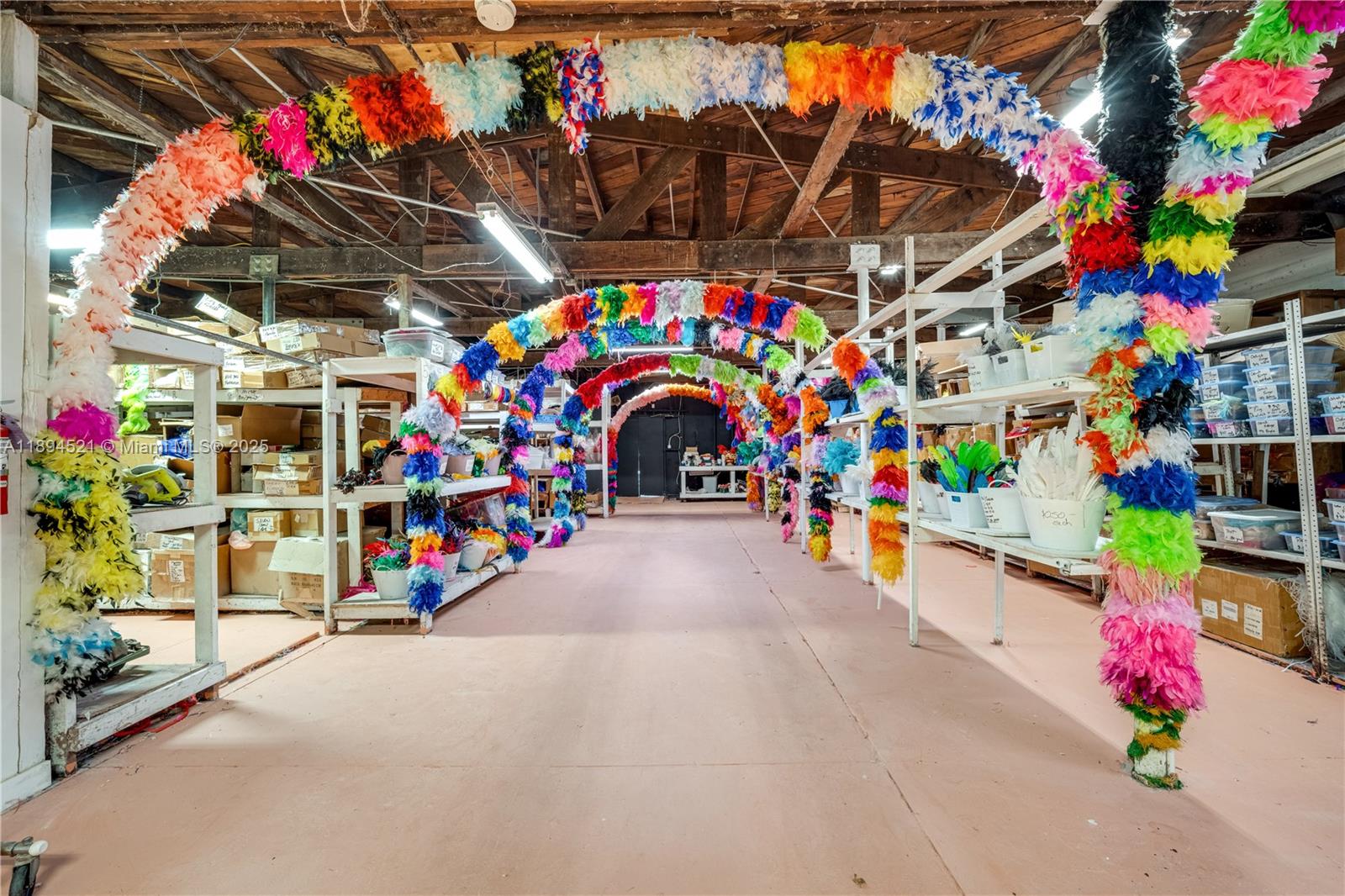 A warehouse space features multiple colorful feather boa arches spanning a central aisle between shelves — 1121 NW 29th St, Miami FL 33127, MIAMI, FL