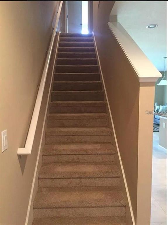 A carpeted staircase with a white handrail leads to a landing in a residential home — 1560 CHELSEA DRIVE, DAVENPORT, FL
