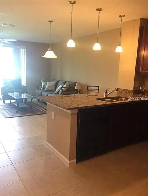 A kitchen island with granite countertops sits in front of a living room with seating — 1560 CHELSEA DRIVE, DAVENPORT, FL