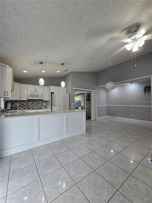 A kitchen with white cabinets and a breakfast bar opens into a tiled dining area — 5401 HOPEDALE DRIVE, TAMPA, FL