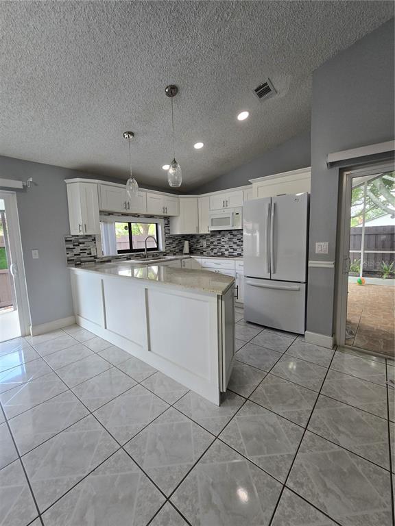 A kitchen features white cabinetry, granite countertops, a tile backsplash, and light-colored floor tiles — 5401 HOPEDALE DRIVE, TAMPA, FL