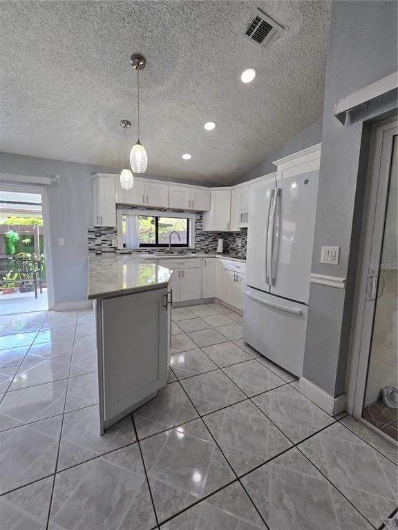 A kitchen features white cabinets, a peninsula, stainless steel appliances, and light-colored tile flooring — 5401 HOPEDALE DRIVE, TAMPA, FL