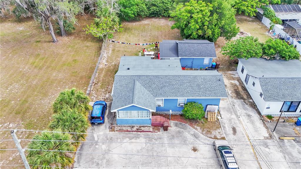 An aerial view shows a blue house with a gray roof, a driveway, and trees — 26 W POLK AVENUE, LAKE WALES, FL