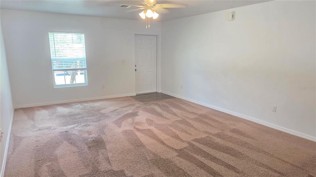 An empty room with beige carpet, white walls, a ceiling fan, and a white door — 2135 19TH AVENUE SW, VERO BEACH, FL