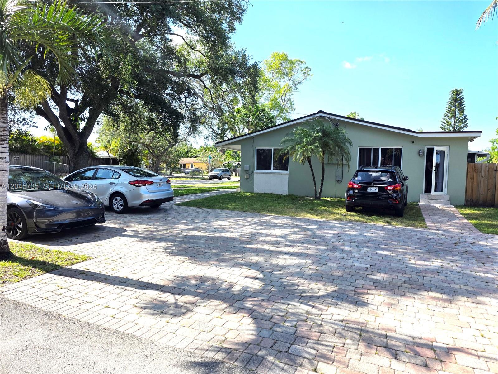 A single-story house with a paved driveway and three parked cars sits under large trees — 2111 N 26th Ave, Hollywood FL 33020, HOLLYWOOD, FL