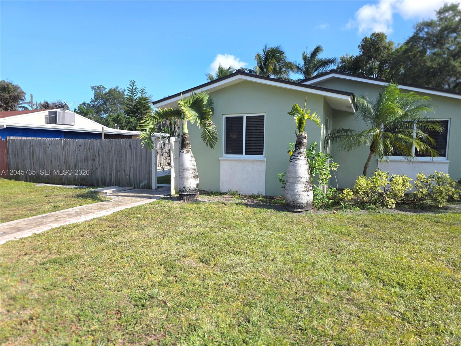 A light green house with two palm trees in the front yard and a fence — 2111 N 26th Ave, Hollywood FL 33020, HOLLYWOOD, FL