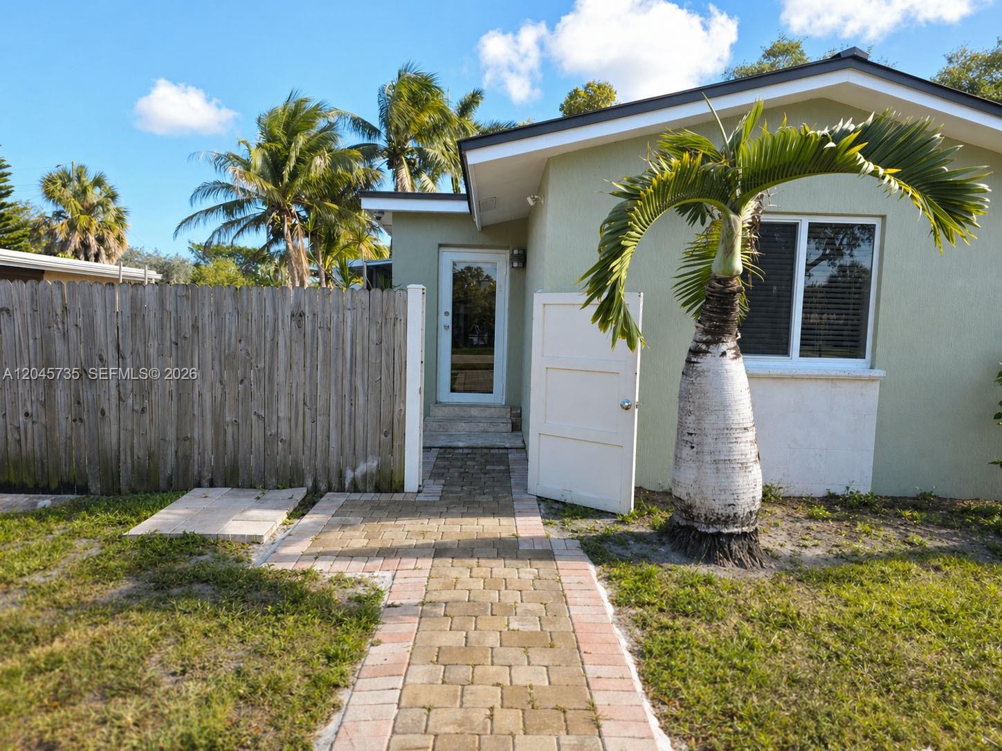 A paved walkway leads to the front entrance of a house with a palm tree — 2111 N 26th Ave, Hollywood FL 33020, HOLLYWOOD, FL