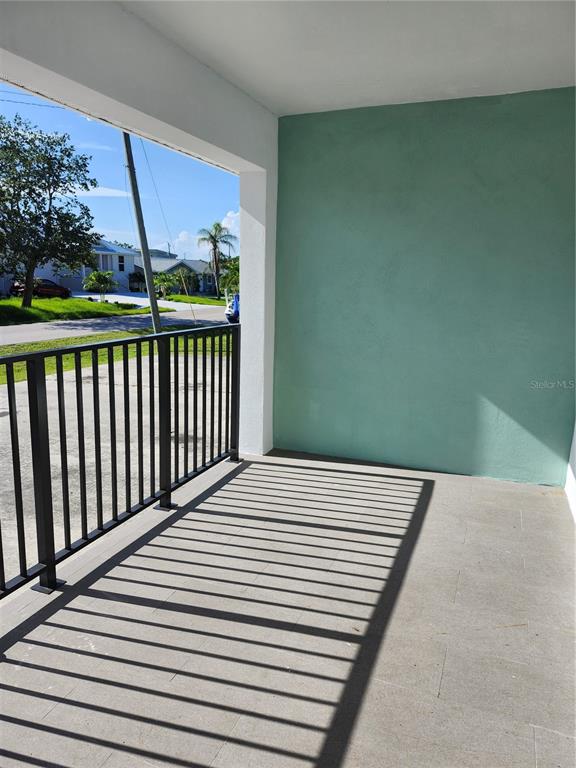 A covered porch features a black metal railing, a light green wall, and tiled flooring — 2921 VASCO STREET UNIT A, PUNTA GORDA, FL