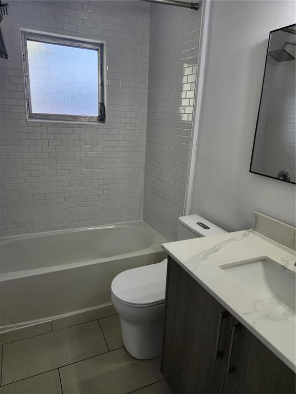 A bathroom features a white subway tile shower, a vanity with a marble countertop, and toilet — 2921 VASCO STREET UNIT A, PUNTA GORDA, FL