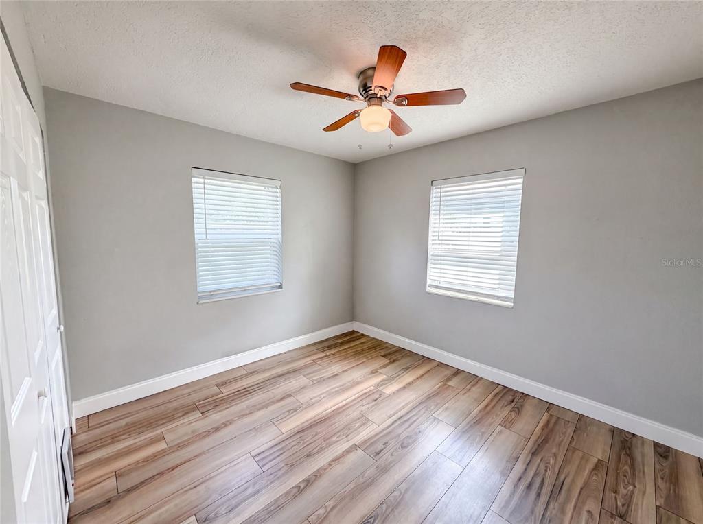 A bedroom features gray walls, wood-look flooring, two windows with blinds, and a ceiling fan — 2242 E DANA DRIVE, DELTONA, FL