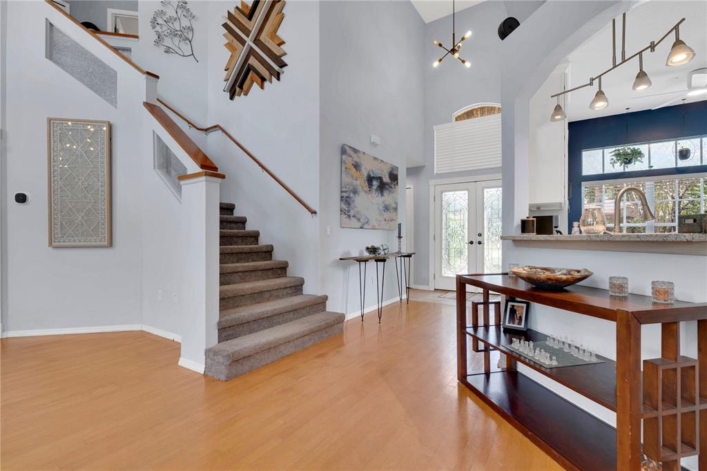 A foyer with light wood flooring, a carpeted staircase, and a view into the kitchen — 5947 DORAVILLE DRIVE, PORT ORANGE, FL