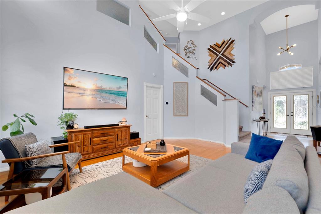 A living room features a vaulted ceiling, a mounted television, a wooden console, and stairs — 5947 DORAVILLE DRIVE, PORT ORANGE, FL