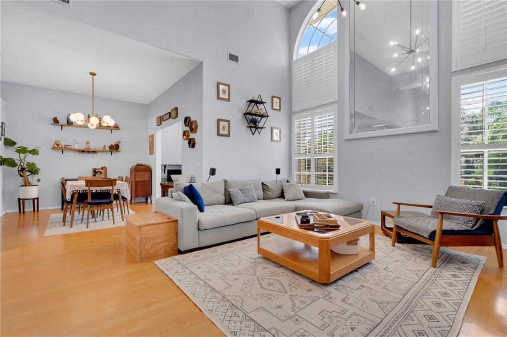 A living room with high ceilings, a sectional sofa, a coffee table, and an adjacent dining area — 5947 DORAVILLE DRIVE, PORT ORANGE, FL