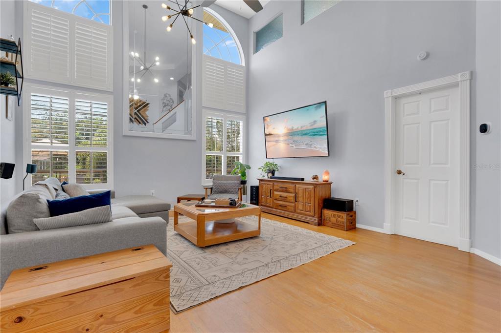 A living room with high ceilings, large windows, a television, and a wooden coffee table — 5947 DORAVILLE DRIVE, PORT ORANGE, FL