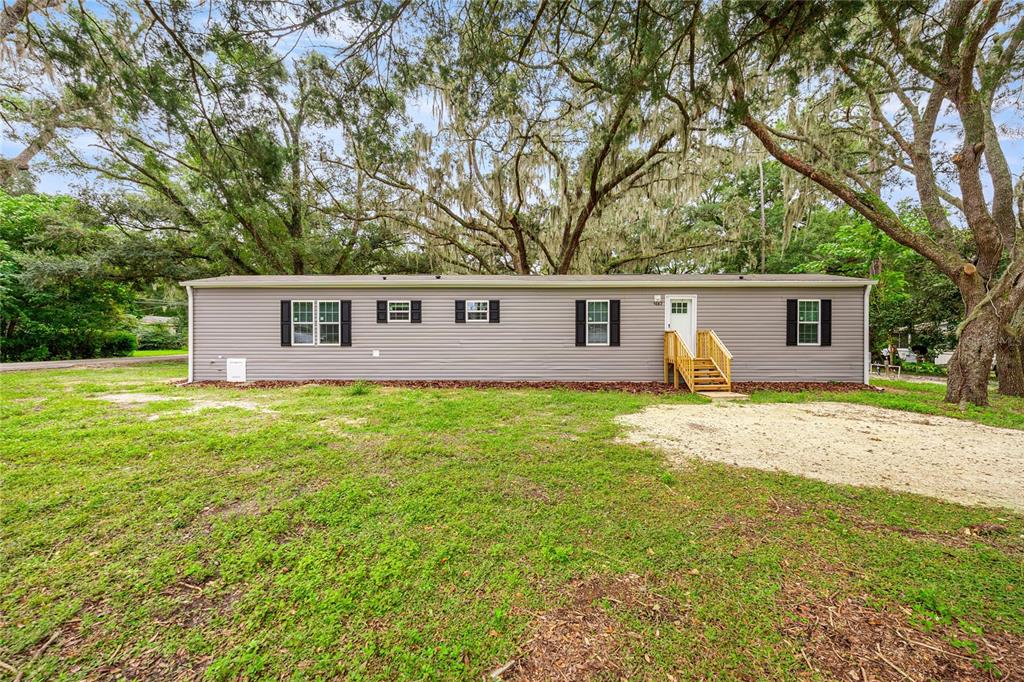 A single-story gray manufactured home with black shutters sits on a grassy lot — 5682 NW 53RD STREET, OCALA, FL