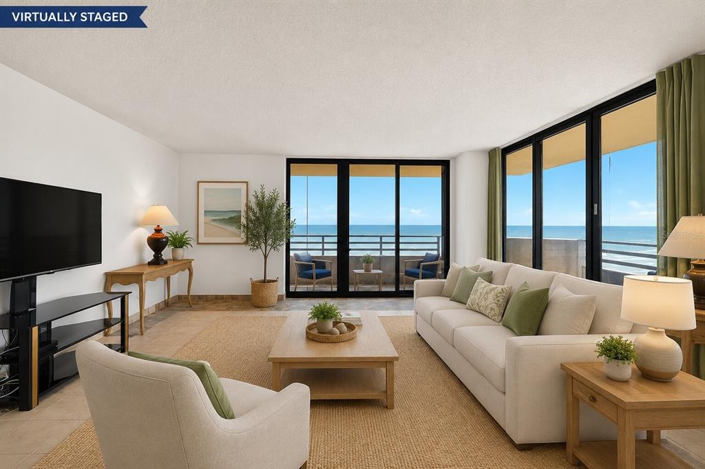 A balcony with outdoor seating overlooks the ocean, beach, and nearby buildings — 1420 N ATLANTIC AVENUE UNIT 1104, DAYTONA BEACH, FL