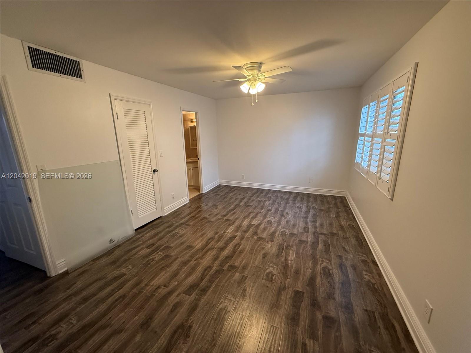 An empty bedroom features wood-look flooring, a ceiling fan, and white plantation shutters — 2606 NE 10 ST # 2606, Hallandale Beach FL 33009, HALLANDALE BEACH, FL