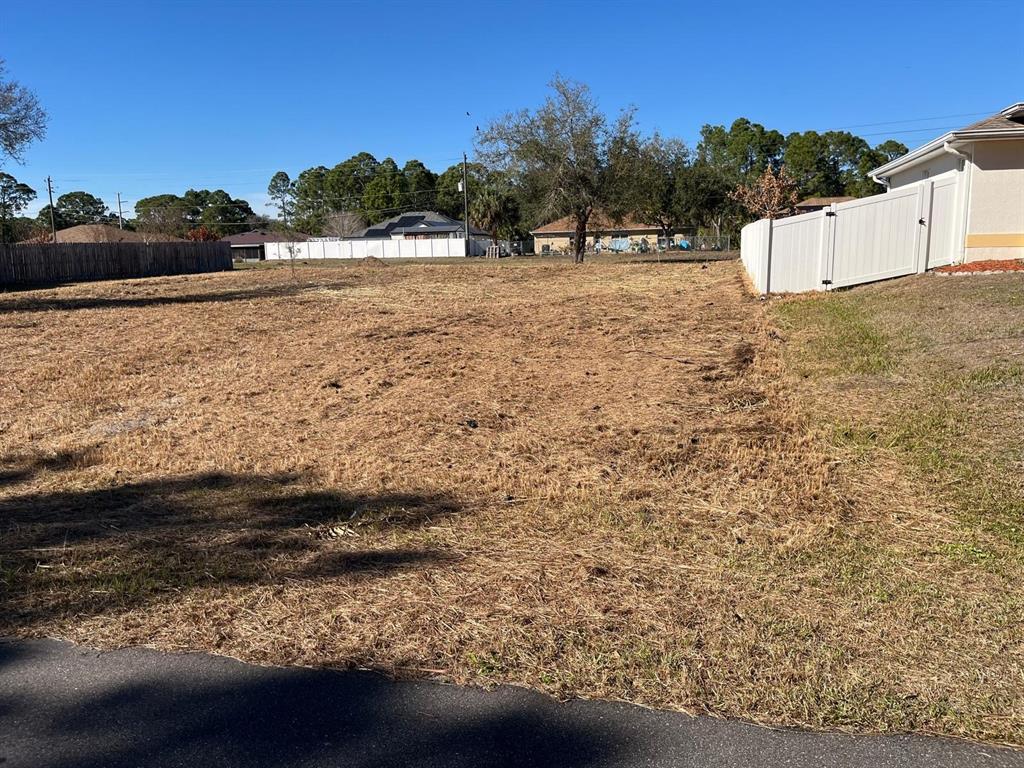 A vacant, grassy residential lot is bordered by white vinyl fencing and neighboring houses — 1181 ALTAMIRA STREET NW, PALM BAY, FL