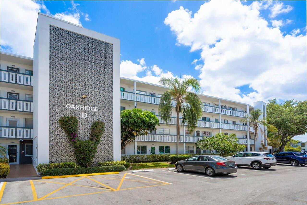 The exterior of a multi-story apartment building labeled Oakridge D with a parking lot — 3024 Oakridge D # 3024, Deerfield Beach FL 33442, DEERFIELD BEACH, FL