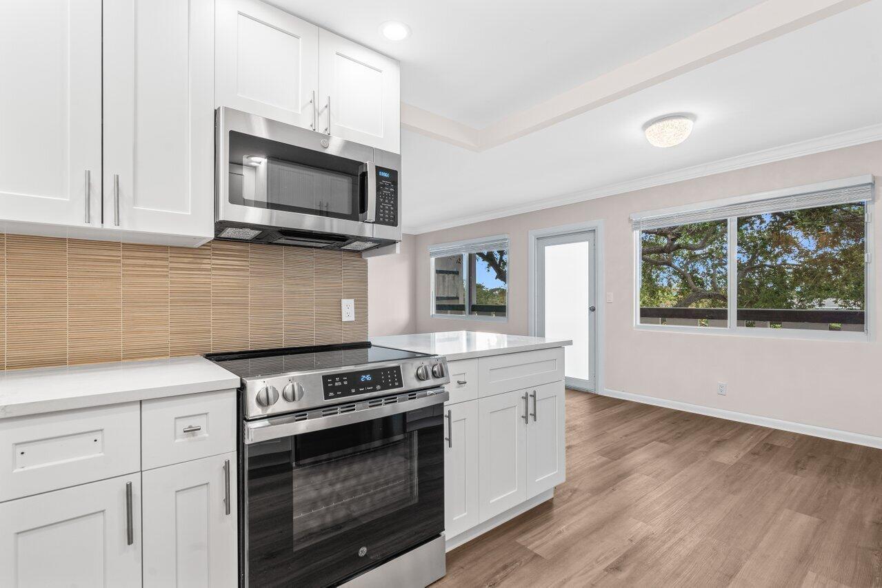 A kitchen with white cabinets, stainless steel appliances, and wood-look flooring — 3024 Oakridge D # 3024, Deerfield Beach FL 33442, DEERFIELD BEACH, FL