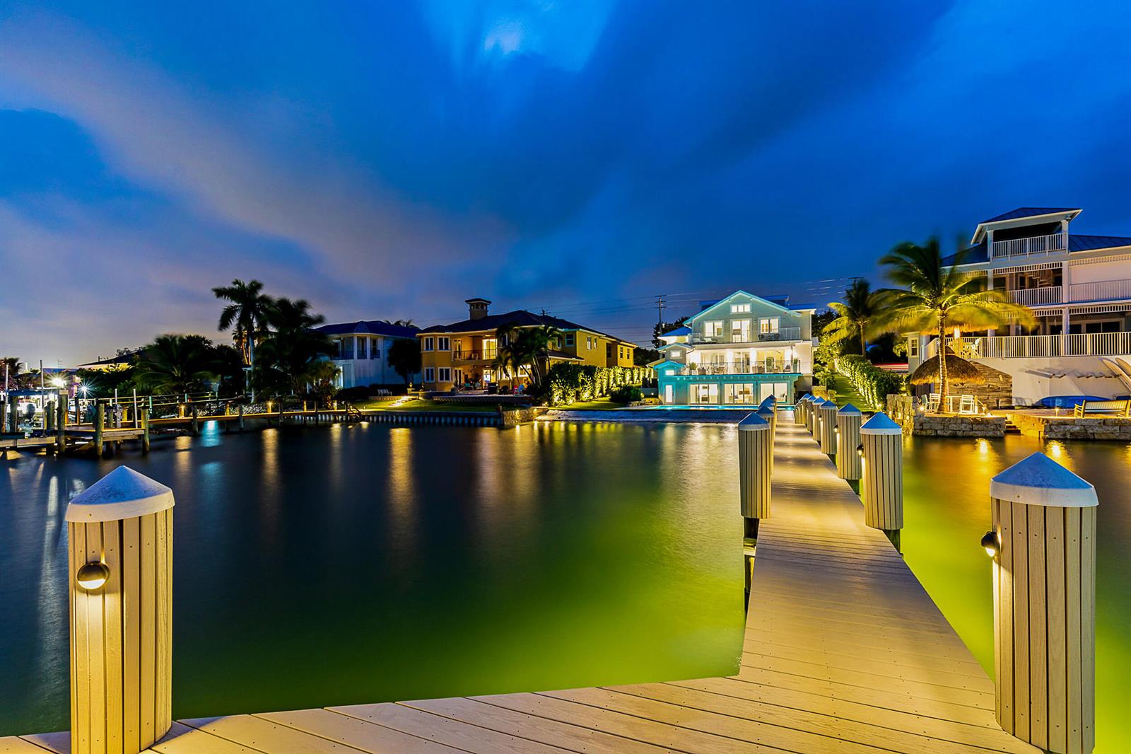 A wooden dock leads toward a multi-story waterfront house at twilight — 18119 SE Federal Highway, Jupiter FL 33469, JUPITER, FL