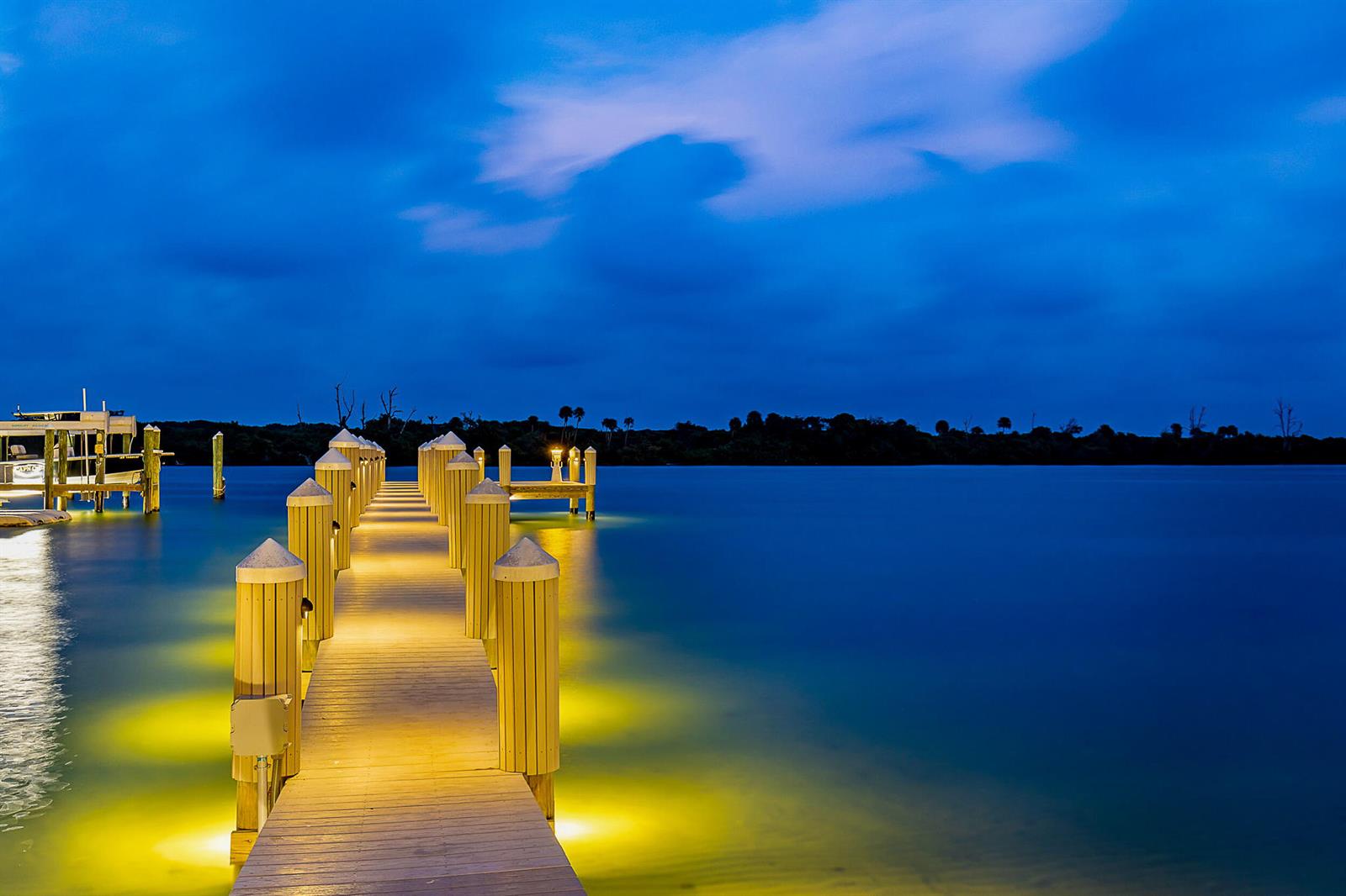 A wooden dock with illuminated posts extends into calm water under a dark blue sky — 18119 SE Federal Highway, Jupiter FL 33469, JUPITER, FL